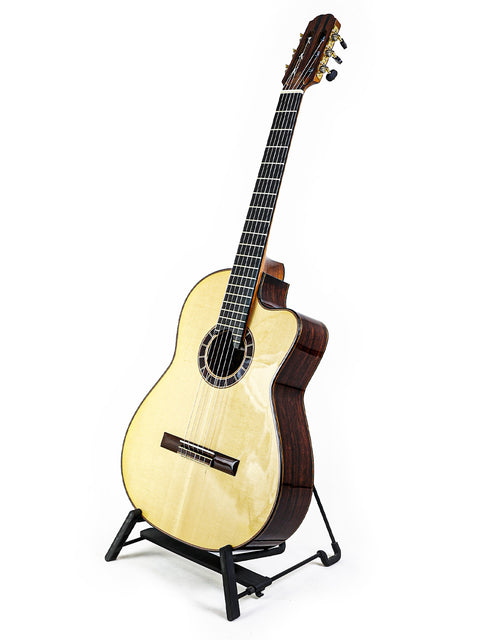 Classical guitar on stand with white background.