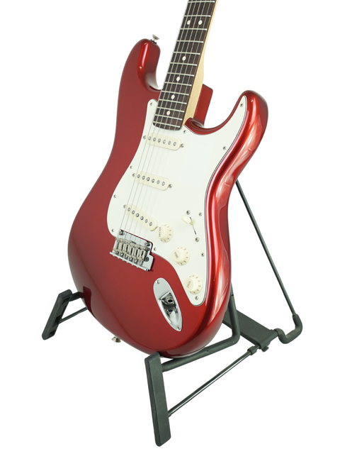 Red electric guitar on a black stand against a white background.