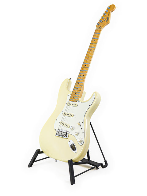 White electric guitar on a black stand against a white background.